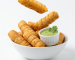 Tequeños venezolanos fritos y crujientes rellenos de queso, servidos en un bowl blanco con salsa cremosa verde